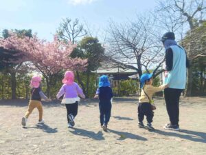 外で遊ぶ園児たちと、見守る先生